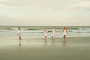 People enjoying a cloudy day at the beach with gentle waves rolling onto the shore.