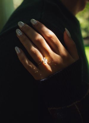 Close-up shots of a hand with an engagement ring sparkling in natural forest lighting.