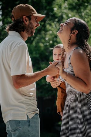 A couple in casual attire shares tender moments with their baby in a series of outdoor photos.