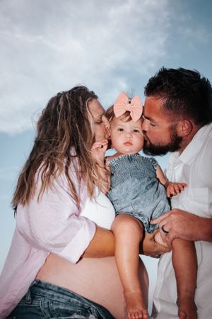 Intimate family portrait outdoors against blue cloudy sky background.