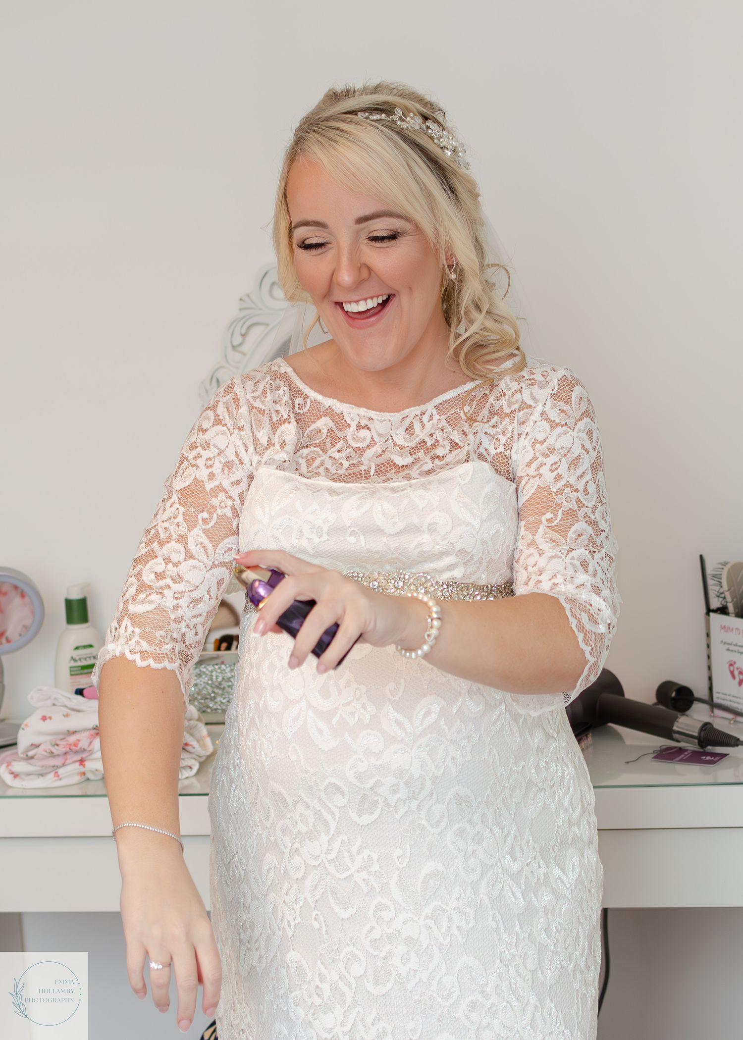 Smiling bride in lace wedding dress with pearl bracelet and tiara getting ready on her wedding day.