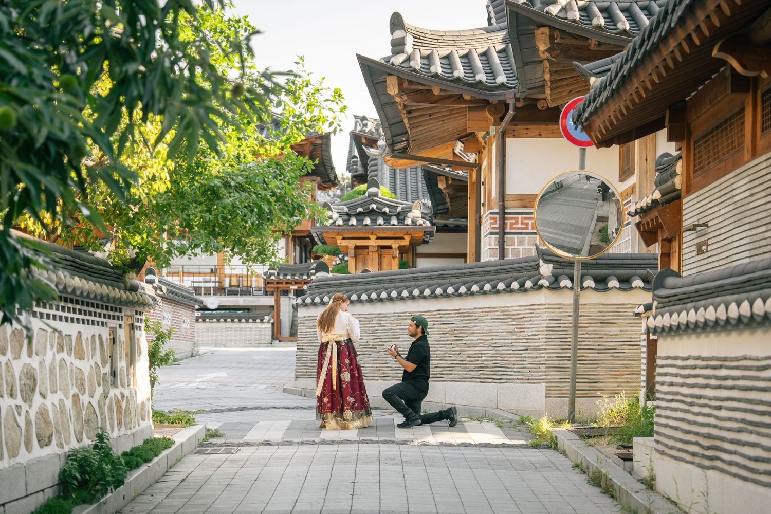 Young couple taking engagement photos at a traditional Korean hanok village in traditional dress.