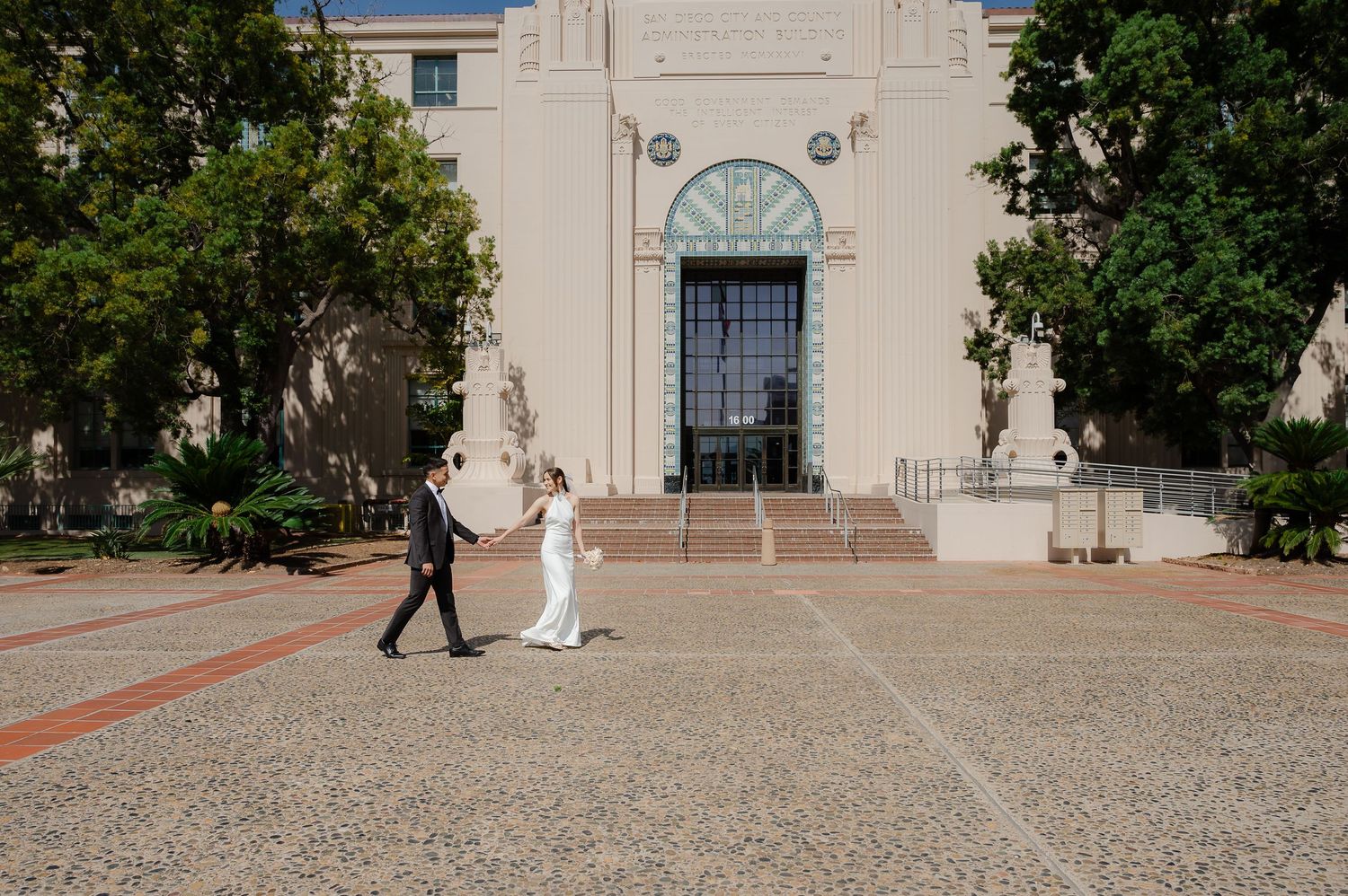 Elopement at county clerks office, couple walking across front of the building holding hands, in love
