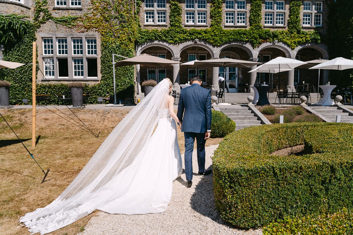Couple walking through a garden path outside Manoir de Lébioles