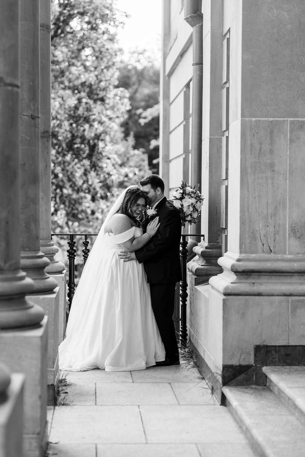 A series of romantic wedding photos showing a couple embracing under elegant stone columns in black and white.