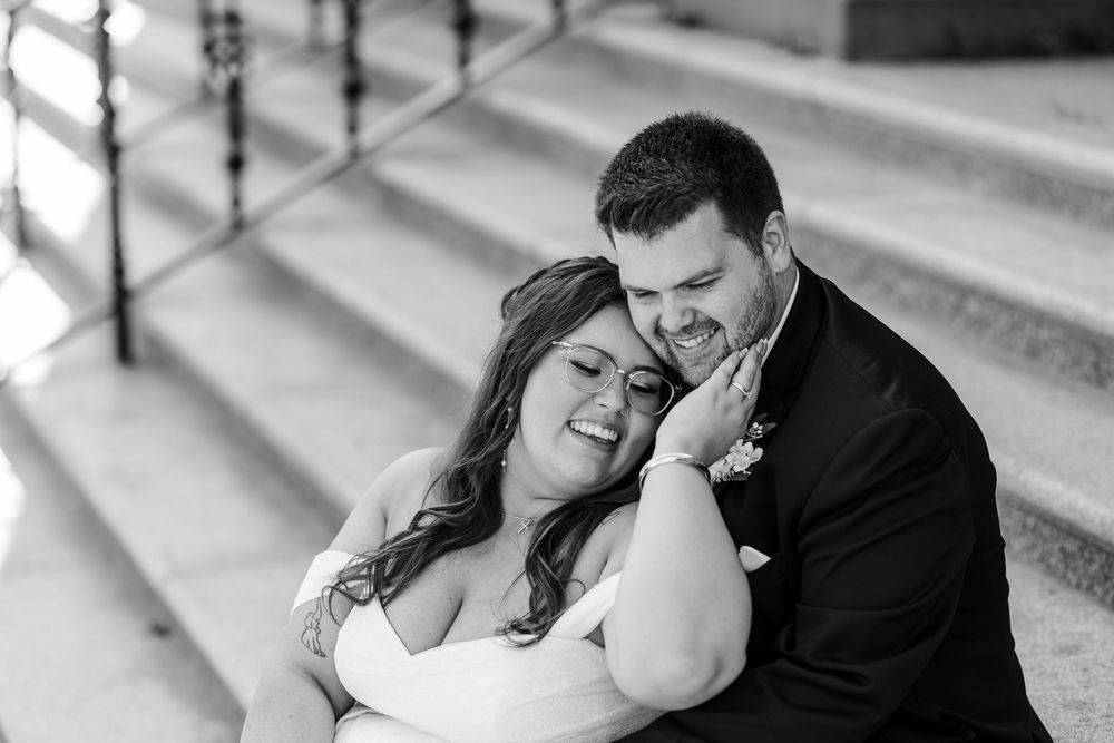 A couple embraces tenderly while sharing a romantic moment in black and white photography.