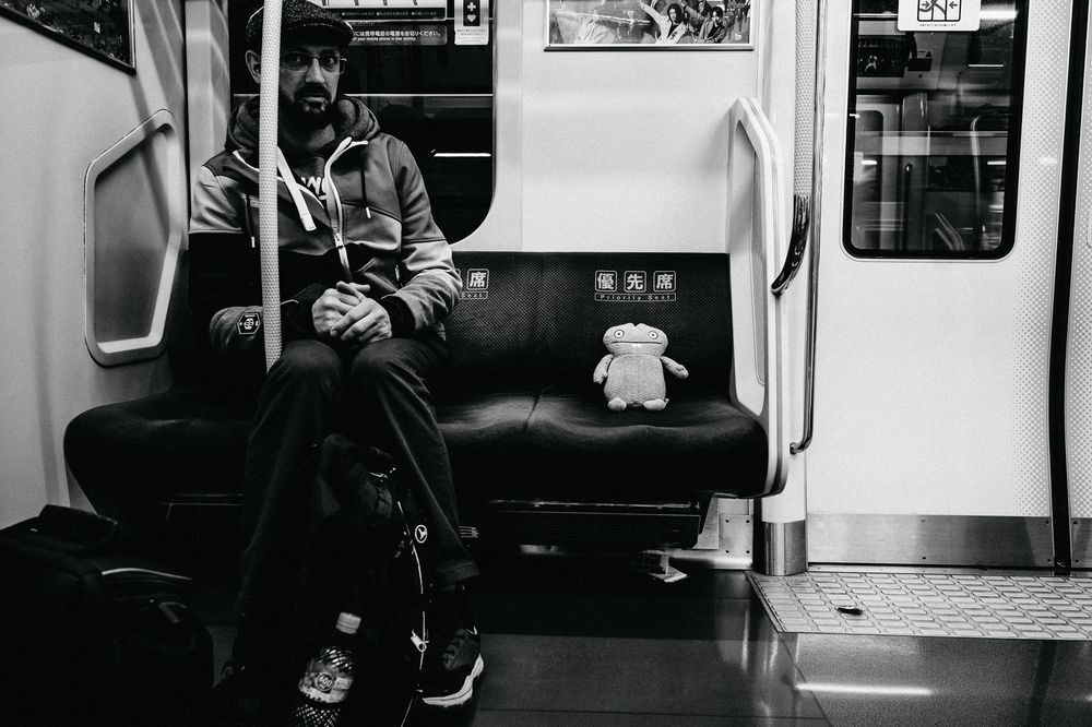 Black and white interior of a subway car with passengers seated.