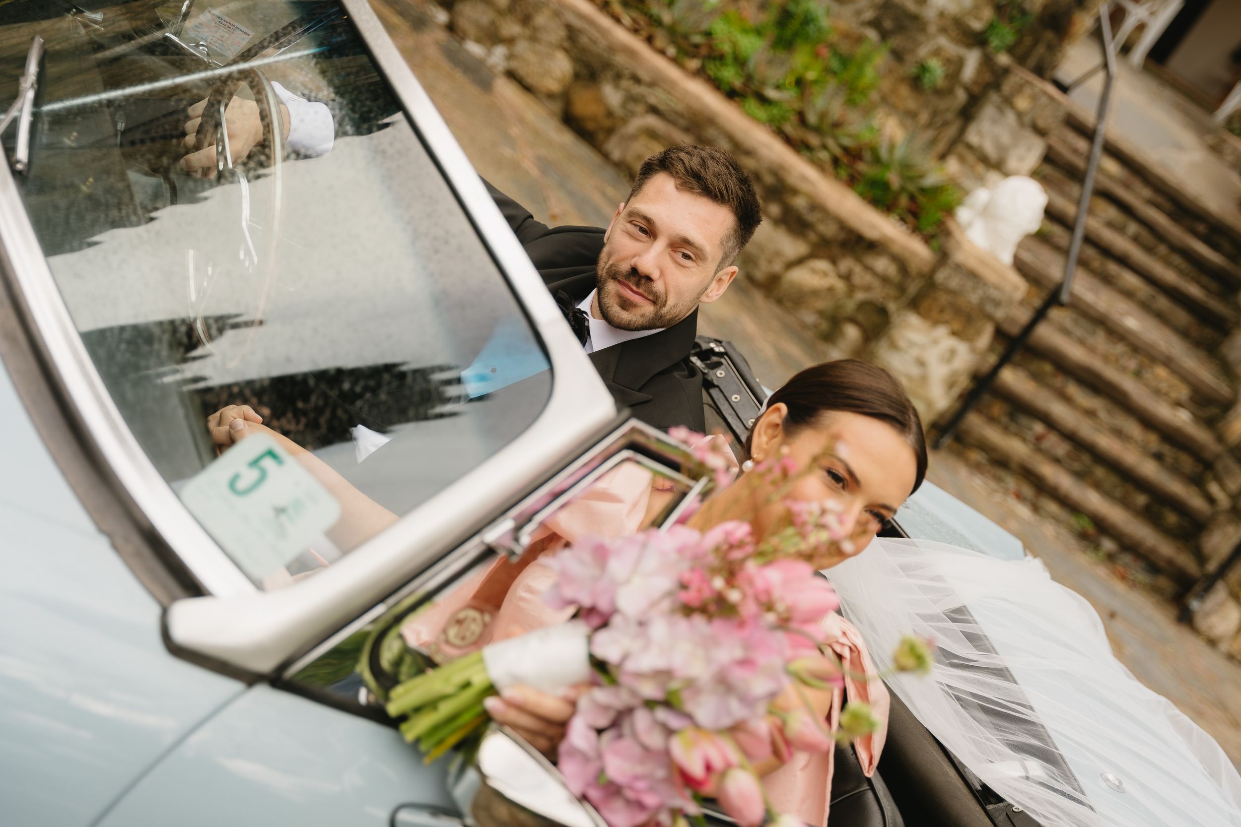 Happy newlyweds sharing a moment in a classic vintage car.