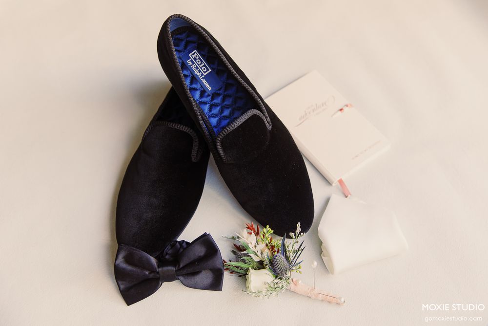 Black dress shoes and floral boutonniere arranged for wedding detail photo.