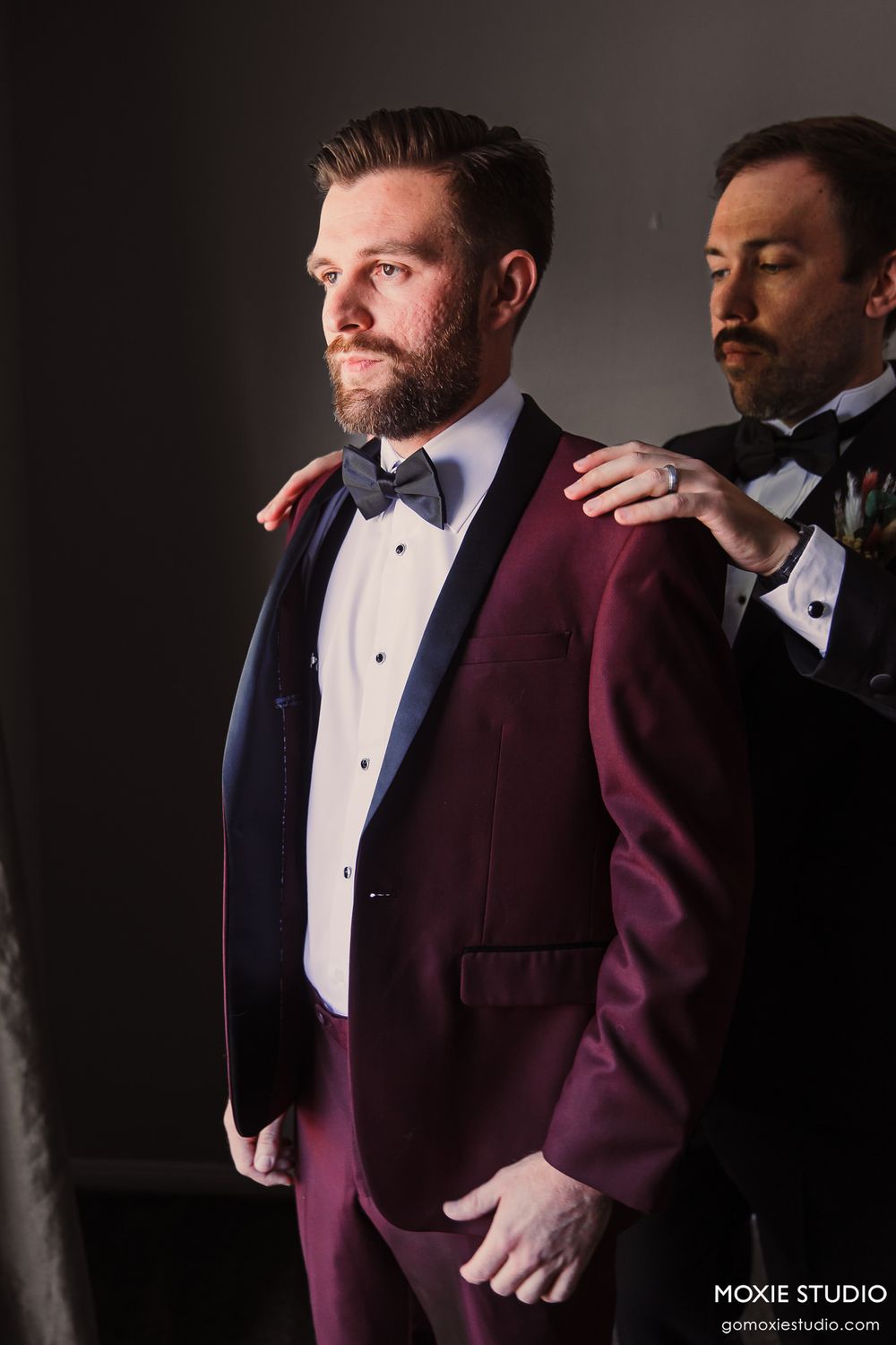 A dramatic portrait showing formal wedding attire in burgundy and black.