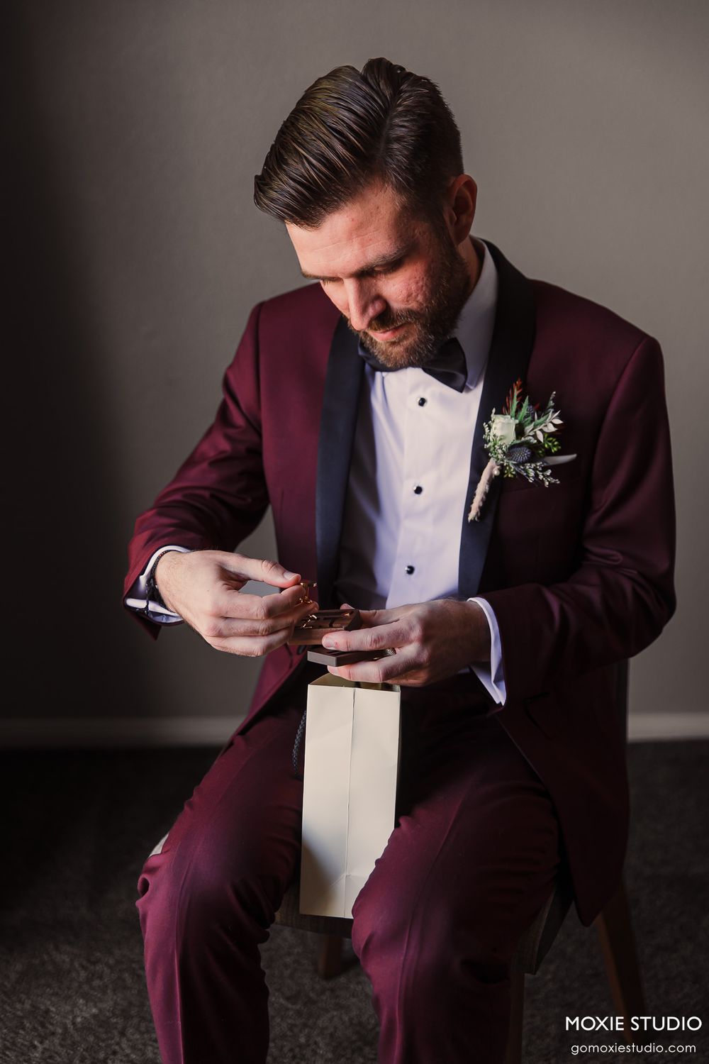 Wedding day preparation scene with burgundy tuxedo and boutonniere details.