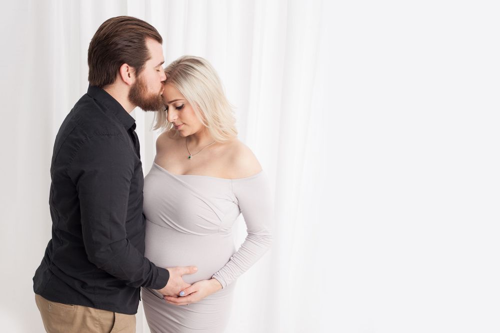 Romantic couple in neutral tones sharing tender moments in minimalist studio portraits from white to dark backgrounds.