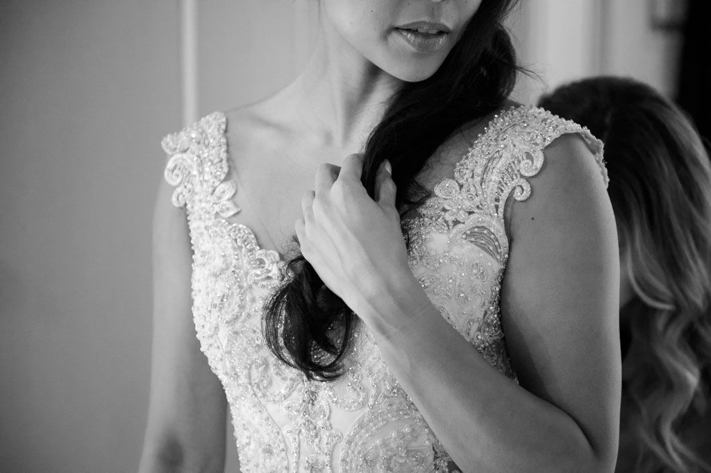 Close up black and white image showing delicate lace details of a wedding dress.