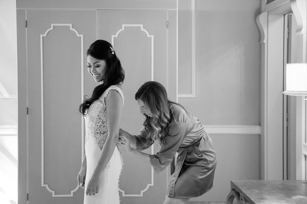 Black and white photo of a wedding dress being adjusted during bridal preparations.