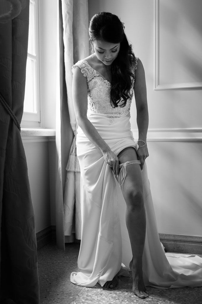 A sequence of black and white photos showing a bride adjusting her dress near a window.
