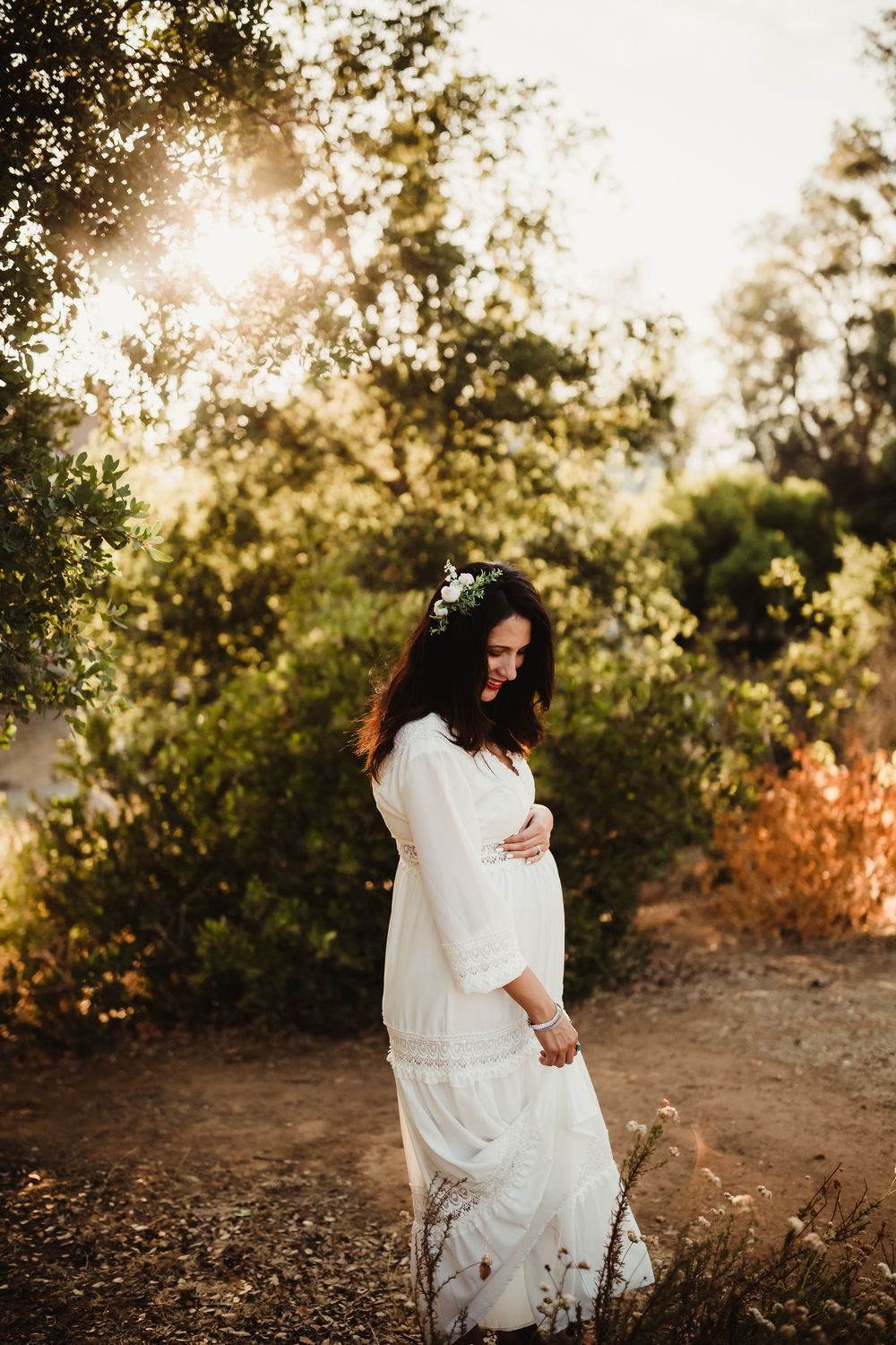 A white dress flows gracefully during a sunset photoshoot in a natural outdoor setting with warm golden lighting.