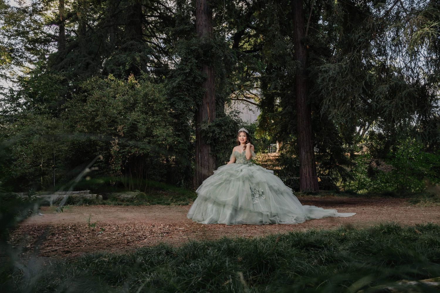 A quince dress flows elegantly in a woodsy outdoor setting as sunlight filters through the trees.