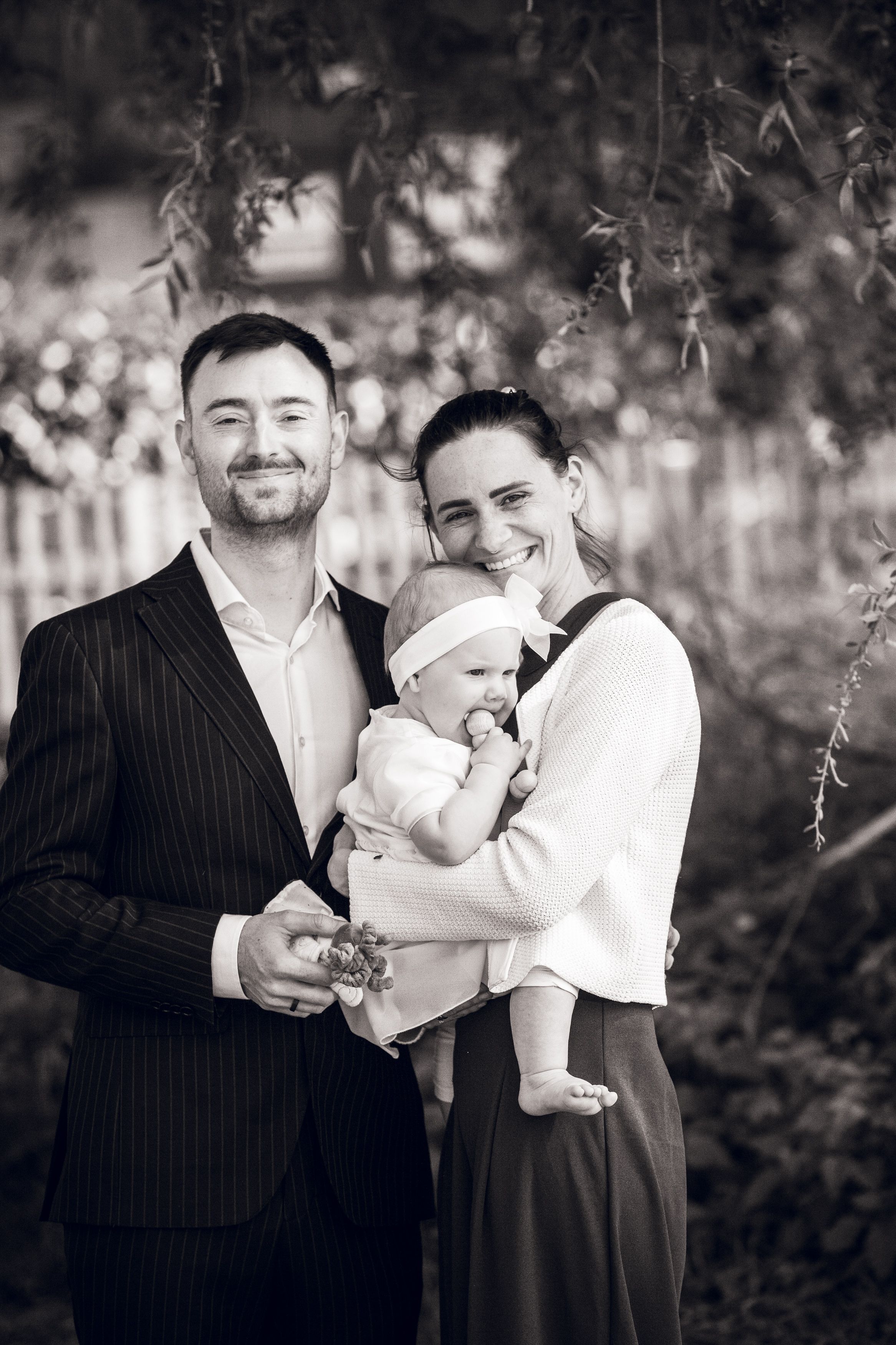 Black and white photo series showing tender family moments between parents and baby in an outdoor setting.