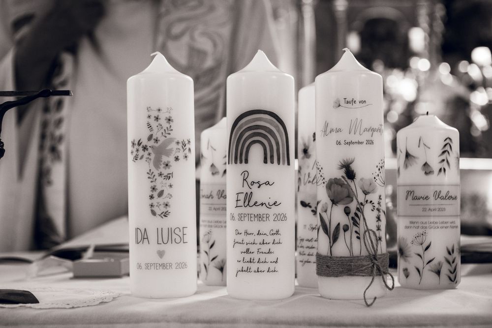 Black and white photo of three personalized baptism candles with floral designs and names including Da Luise and Rosa Eliane.