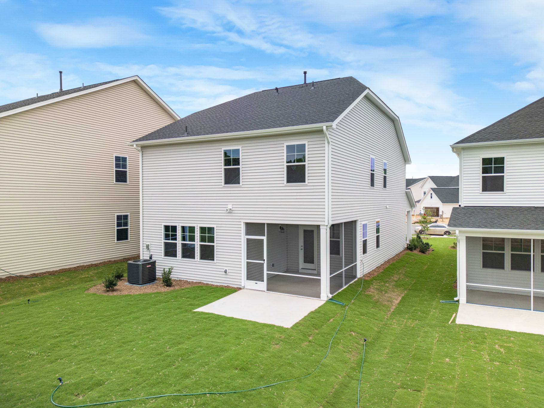 Rear view of modern suburban homes with large backyards and patios.