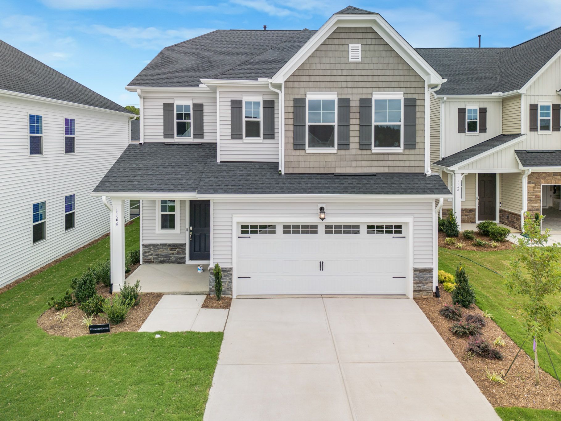 Street view of new construction homes with attached garages in a residential development.