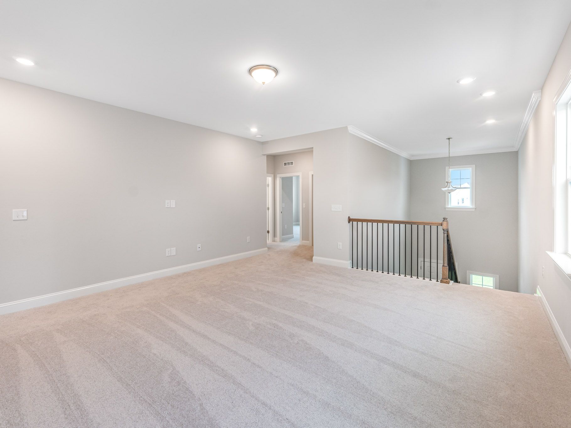 Large open concept living area with gray walls, recessed lighting and plush carpeting.