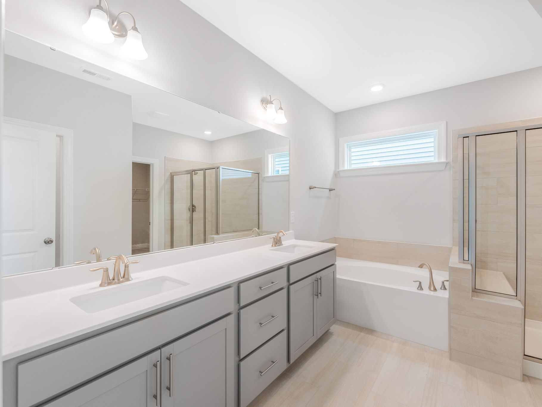 Long white bathroom vanity with double sinks, mirrors, and modern fixtures in a bright setting.