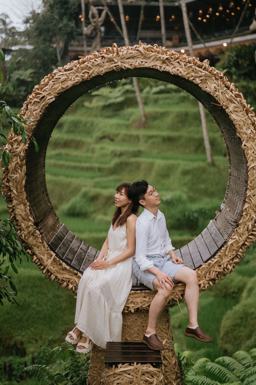 A couple relaxing on a woven nest swing overlooking terraced rice fields.