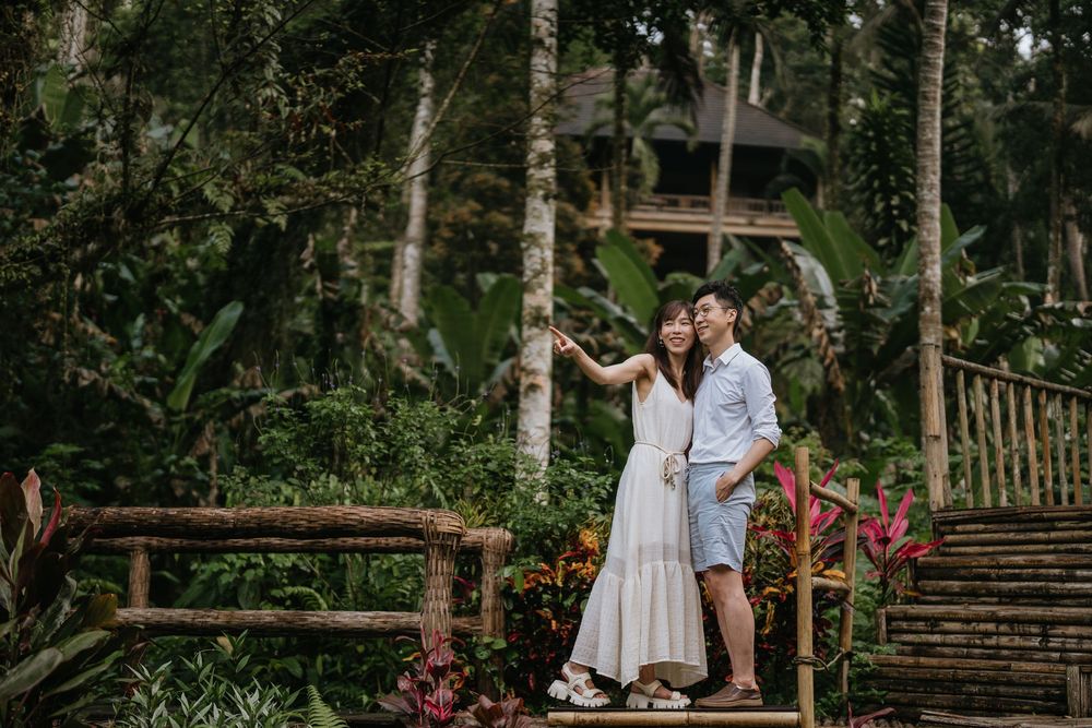 A couple shares an intimate moment on rustic wooden steps surrounded by tropical greenery.
