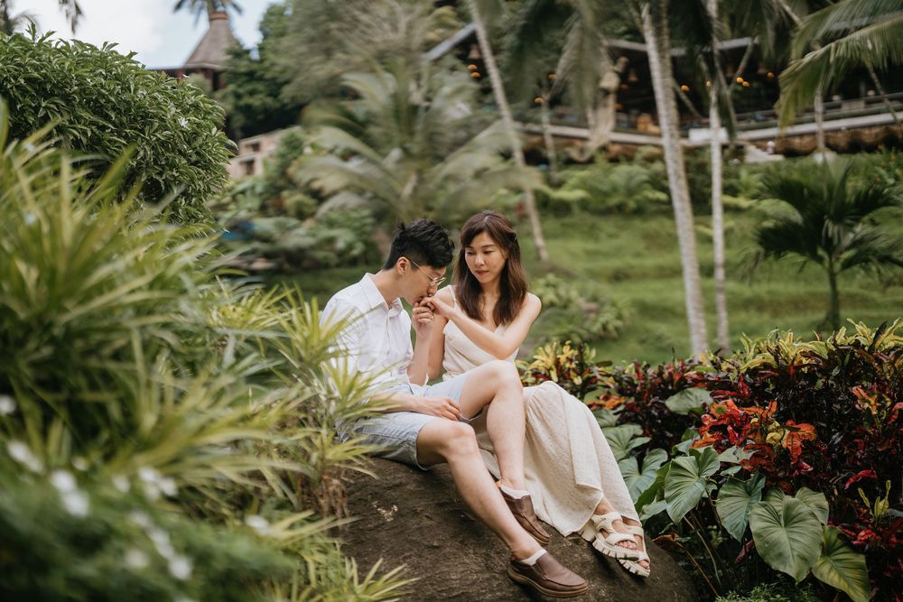 A romantic outdoor photoshoot in a tropical garden with palm trees and colorful flowers.