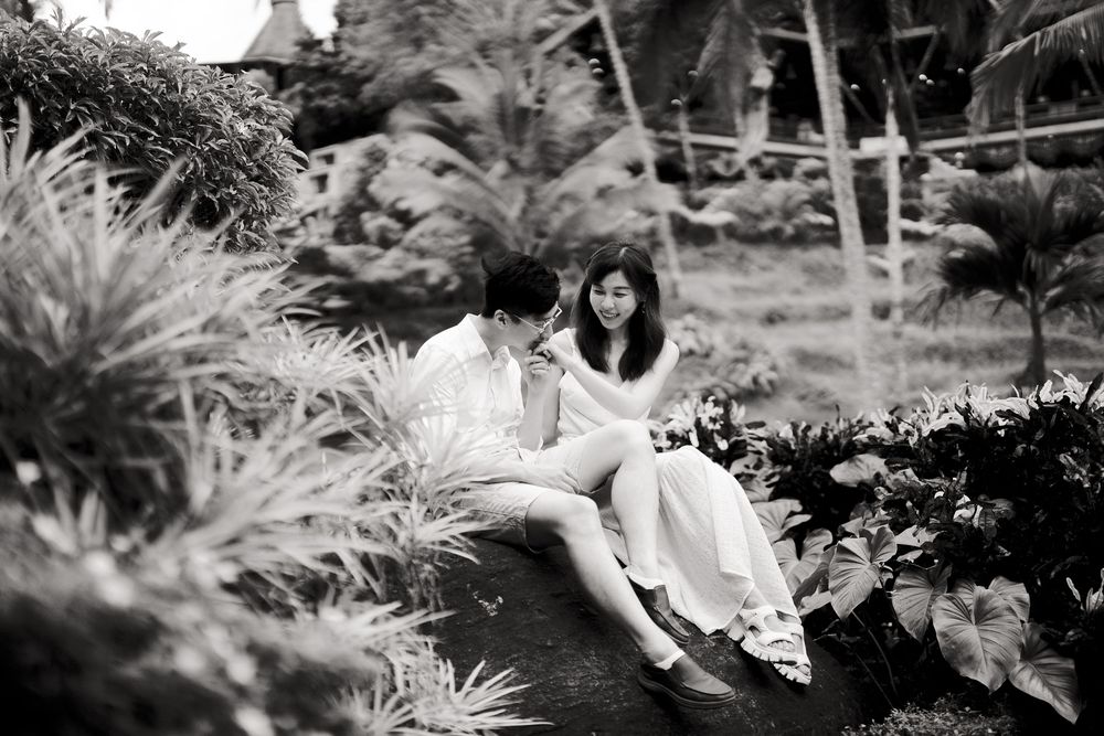 A black and white artistic photo of a couple in a tropical garden setting.