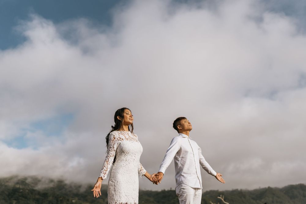 A couple in white outfits enjoying a moment under cloudy skies.