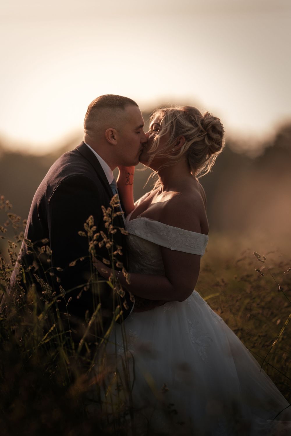 Romantic silhouette of a couple kissing in a golden field at sunset, creating a dreamy and tender moment.