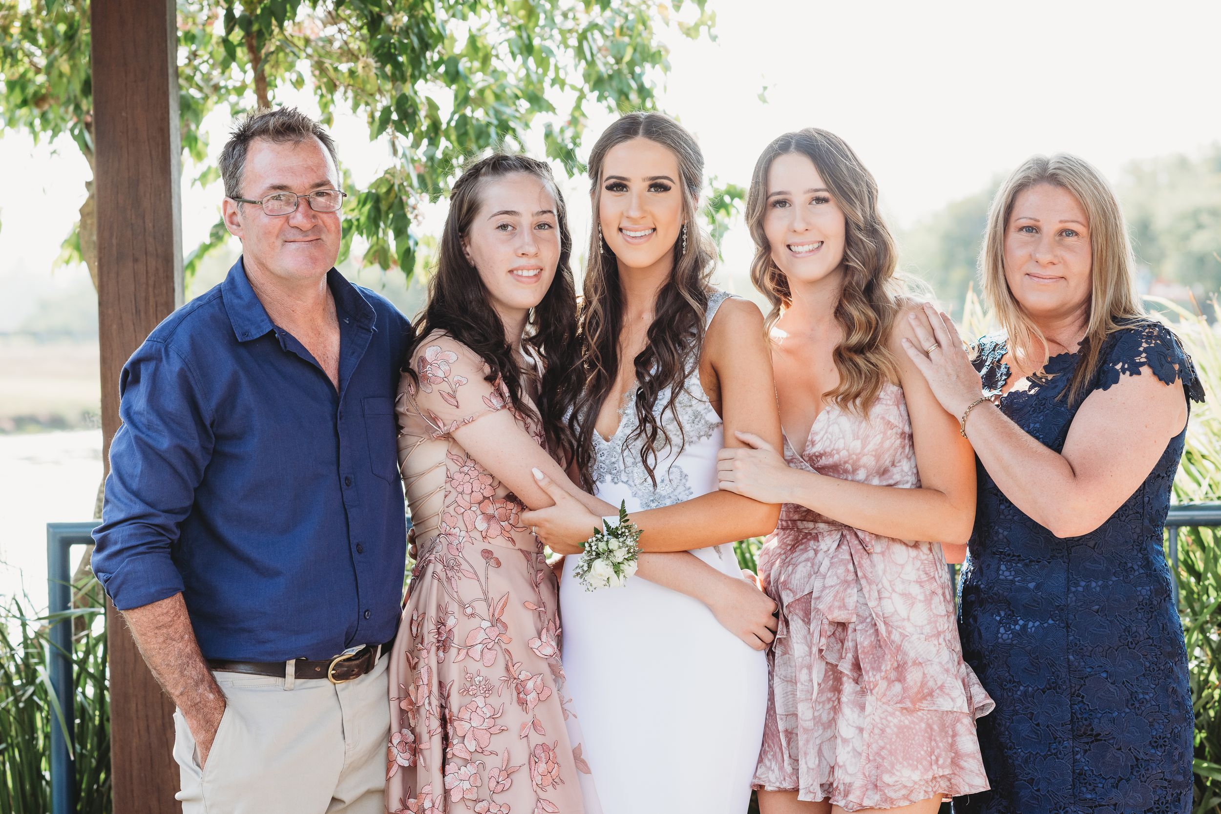 Wedding party group photo outdoors with bride in white and attendants in pink dresses.