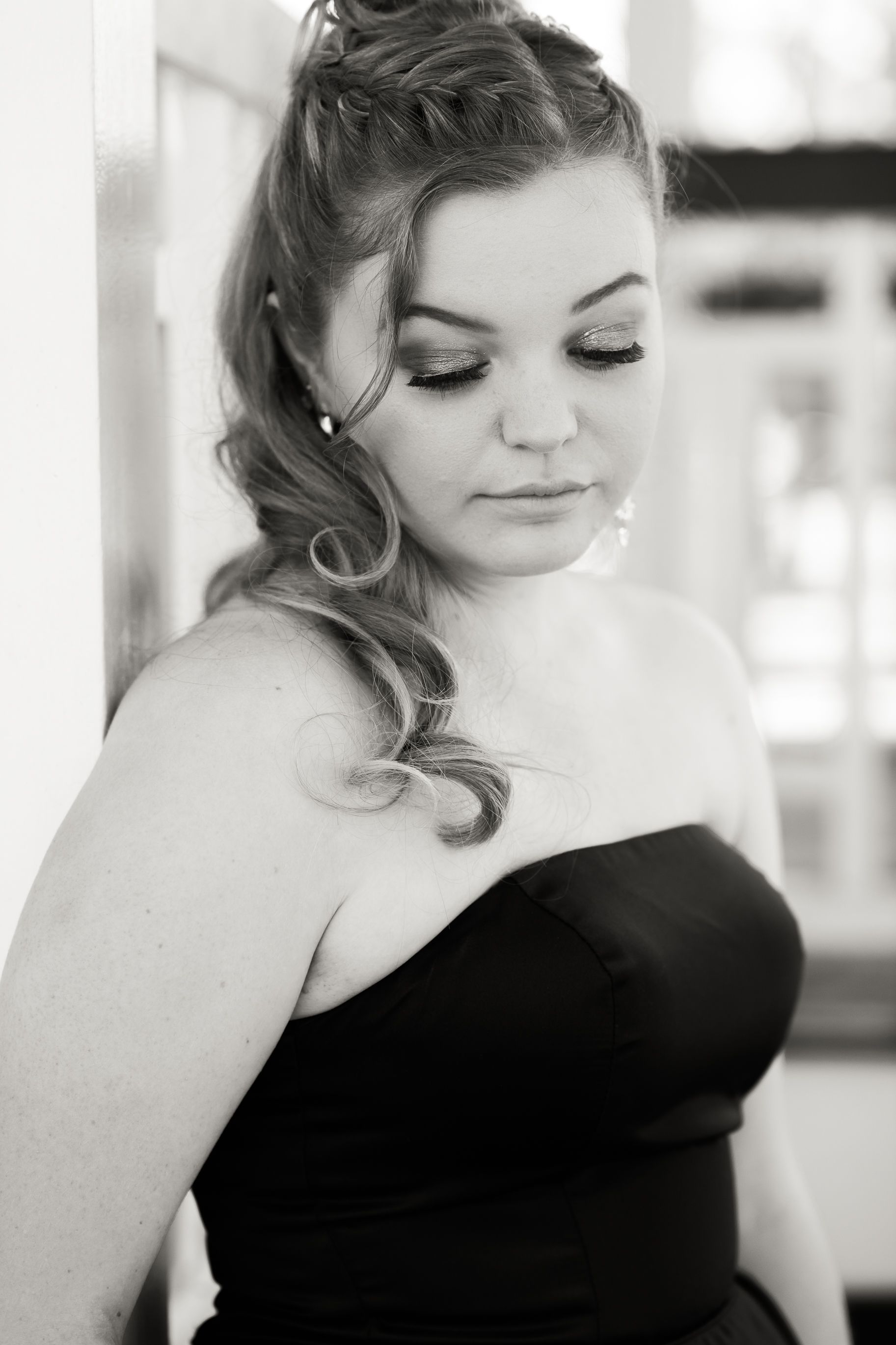 Black and white portrait showing elegant hair styling and makeup with eyes closed.