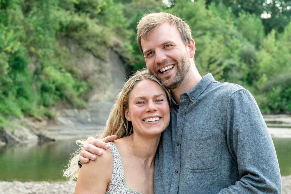 A couple shares a sweet moment together by the riverside surrounded by lush greenery at Brecksville Reservation for a Family Photo Session