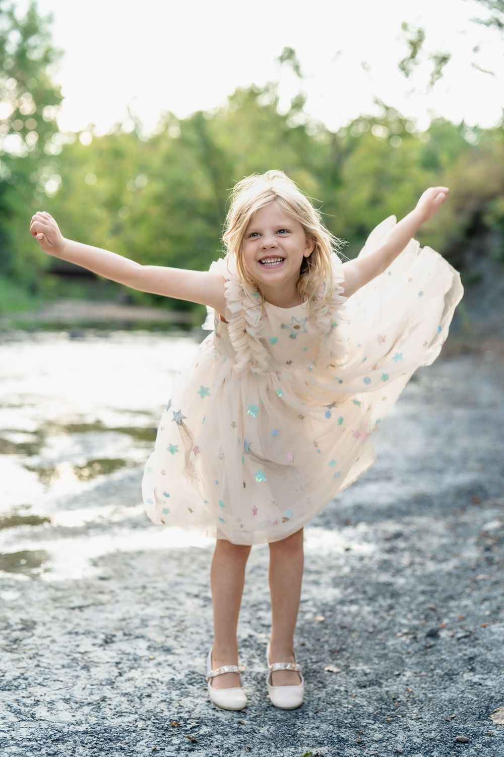 Joyful child in a polka dot dress poses playfully outdoors on a sunny day at Brecksville Reservation for Family Photo Session in Cle, Ohio