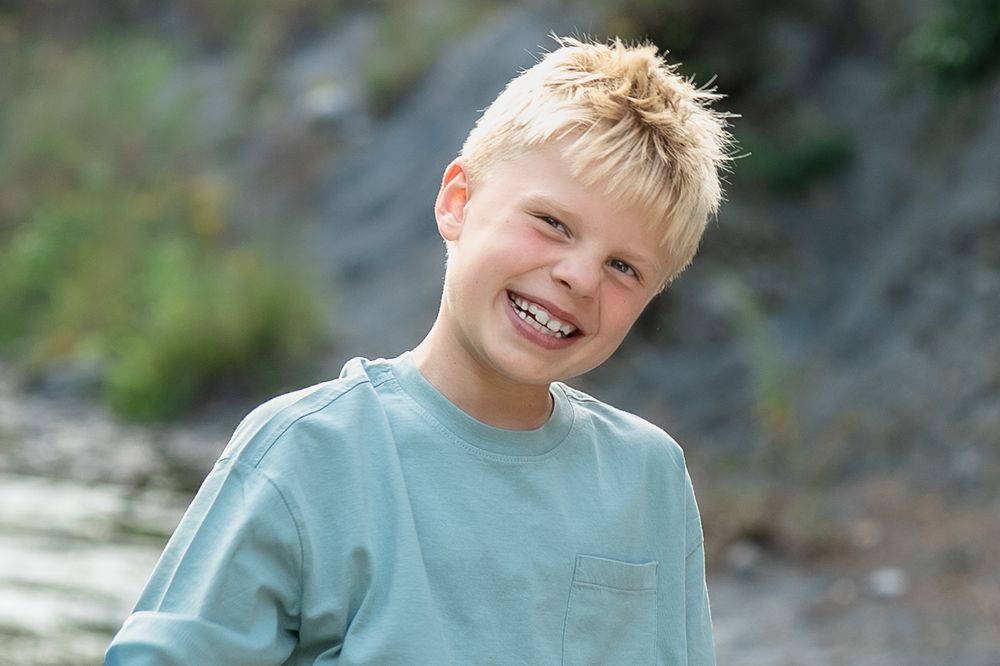 Boy in light blue t-shirt smiles brightly while playing outside at Brecksville Reservation Family Photo Session in Cleveland, Ohio