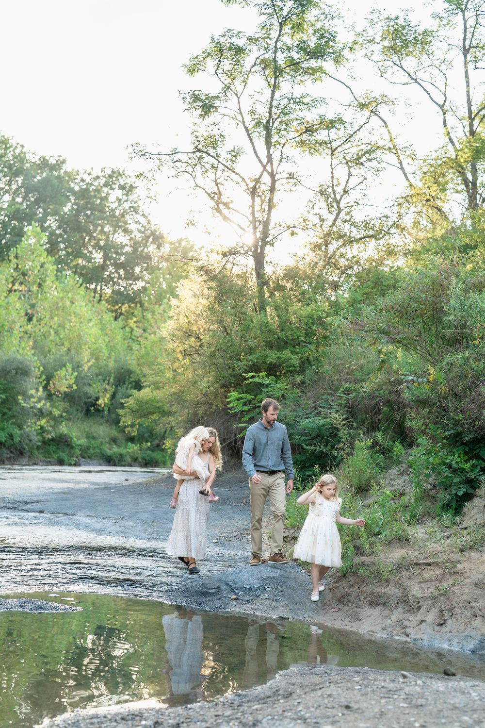 Family enjoying a relaxing afternoon walking along a scenic creek bed surrounded by lush greenery at Brecksville Reservation for family pics