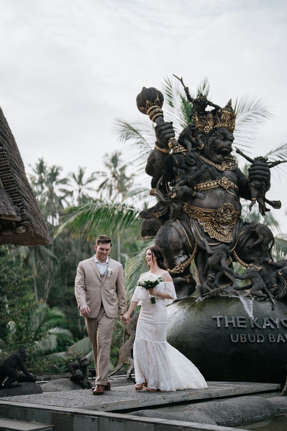 Wedding couple posing by traditional Balinese statue at The Kayon resort in Ubud.