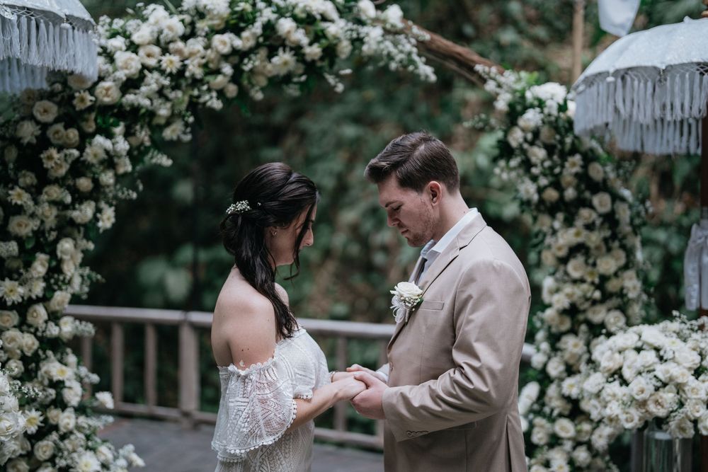 Intimate wedding moments captured near a decorative white flower arch.
