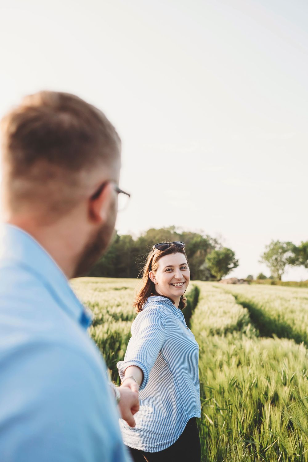 Couple takes romantic walk through a golden wheat field at sunset as they enjoy precious moments together in nature.
