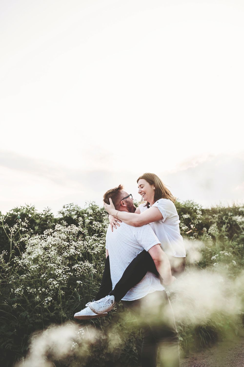 Couple sharing intimate moments while lying in a grassy meadow on a bright summer day.