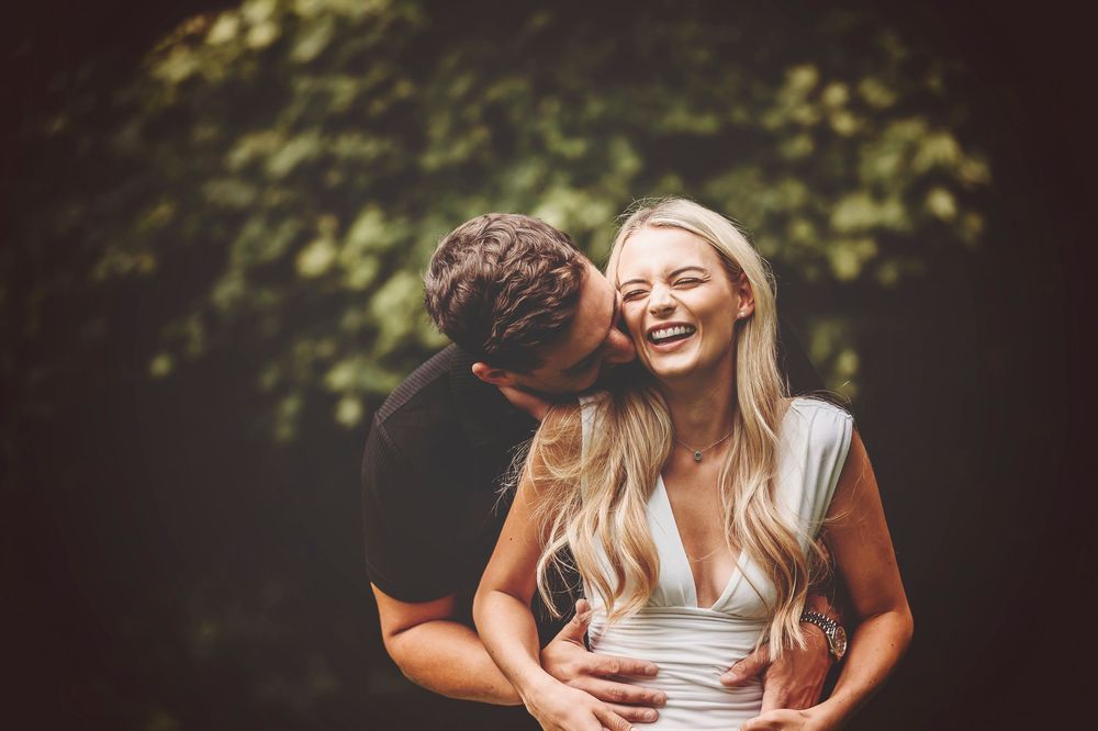 Romantic outdoor couples photoshoot showing affectionate embrace in natural forest setting.