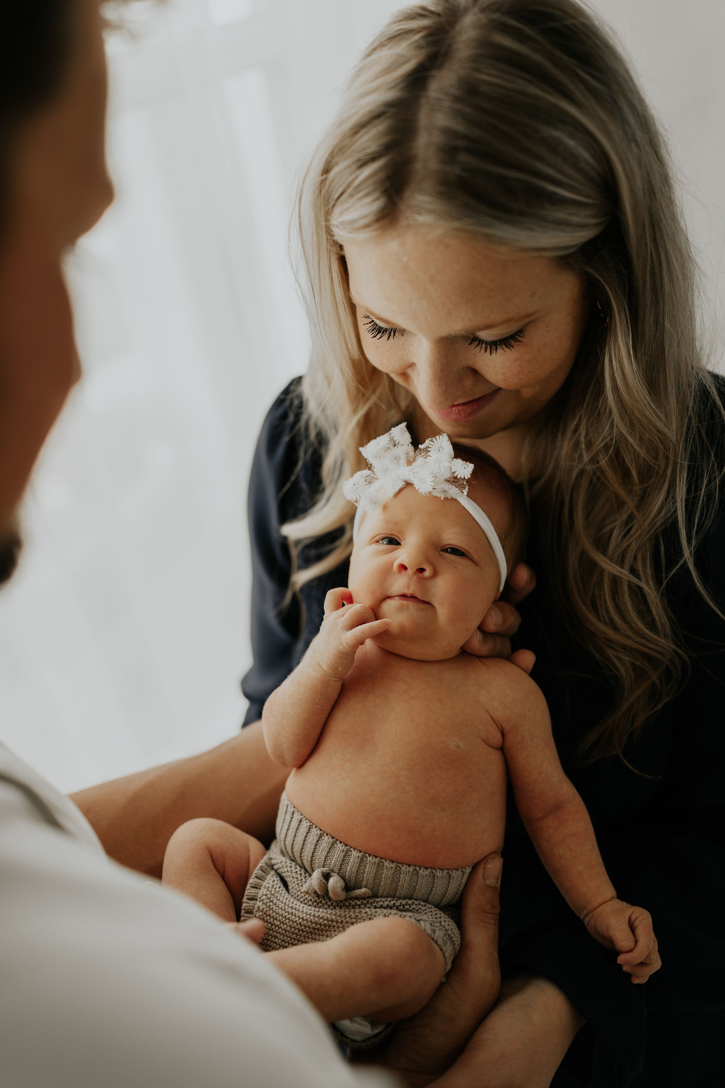 A tender moment captured in four intimate photos showing parent and baby bonding against a light backdrop.