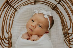 A collage of five black and white photos showing a sleeping baby wearing a white bow headband.