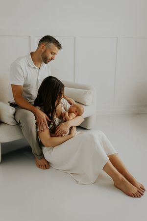 Couple in intimate photoshoot wearing white and grey clothing against minimalist background.