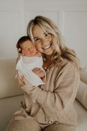 A series of tender moments captured between parent and newborn baby in a light, airy setting wearing neutral knit sweater.