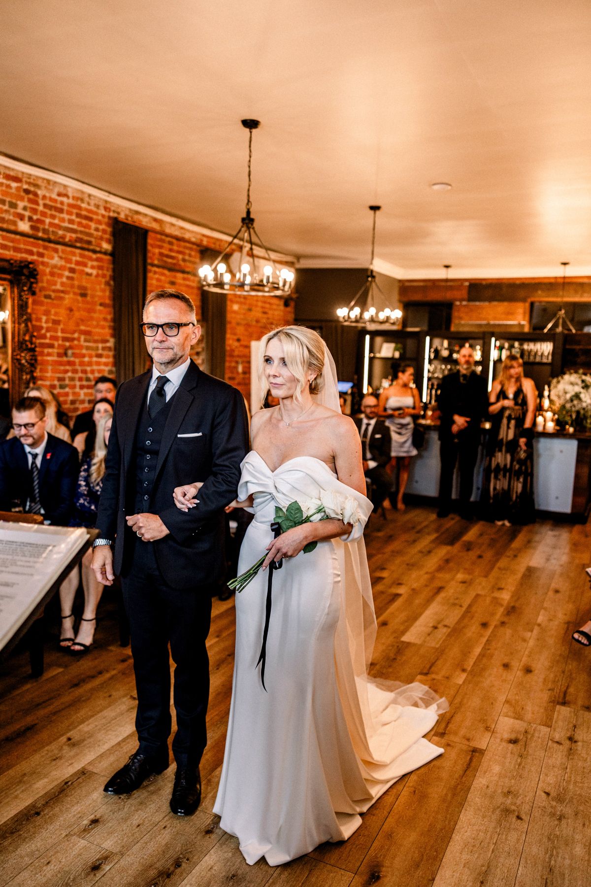 Bride and groom walking hand in hand near lakefront venue in Ontario