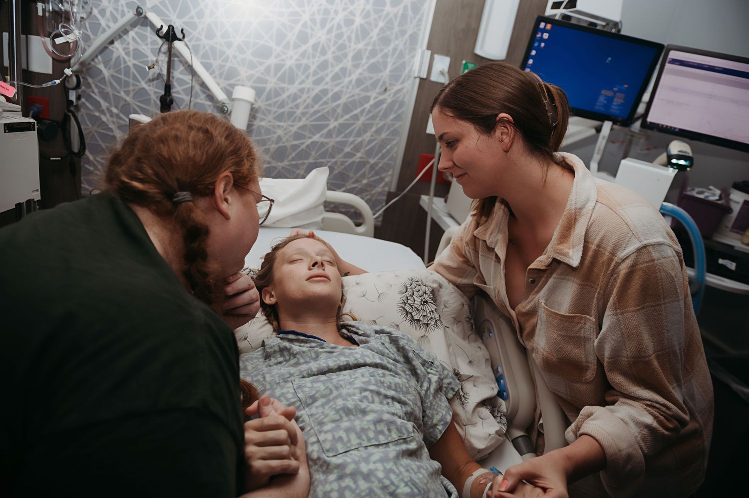 Three people share an emotional moment together at a hospital bedside while a woman is giving birth at Nacogdoches Medical Center.